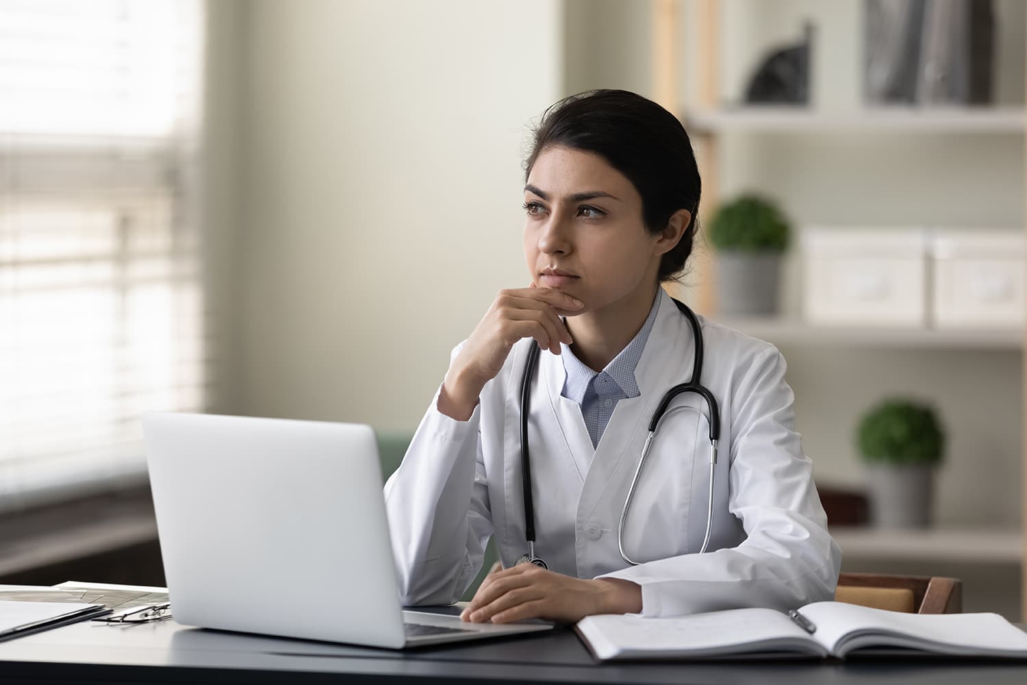 Physician at a computer considering contactless patient intake software solutions.